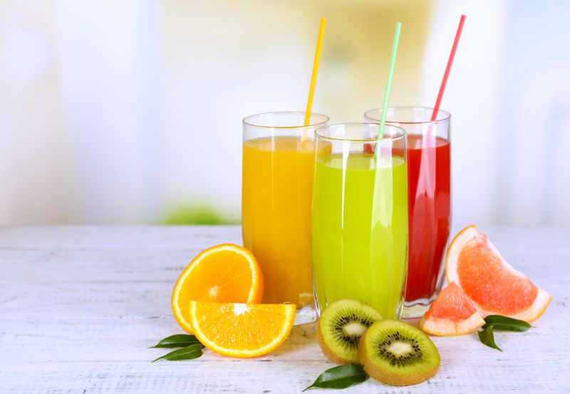 Trzy szklanki z sokami owocowymi - grejpfrutowym, pomarańczowym i z kiwi.