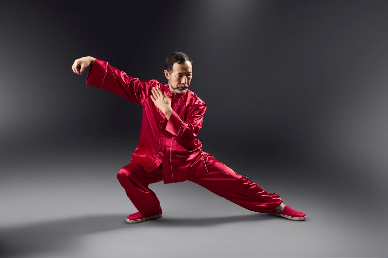 Mężczyzna w czerwonym kimonie, ćwiczący Tai Chi.